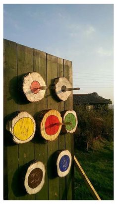 an outdoor archery target set on a wooden board with arrows in different colors and shapes