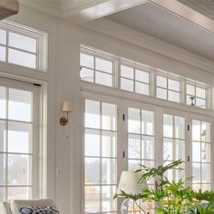 a living room filled with lots of windows next to a white couch and two chairs