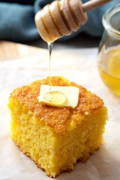 a piece of cake with butter on top and honey being drizzled over it