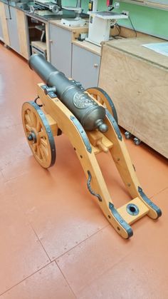 an old cannon sitting on top of a table in a room with wooden cabinets and counter tops