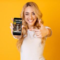 a woman is holding up her cell phone to show the screen with both hands and smiling