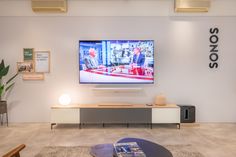 a flat screen tv sitting on top of a white wall next to a wooden table