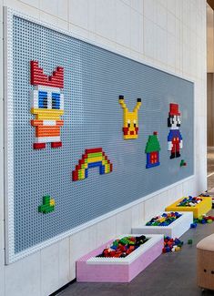 a wall with legos on it in the middle of a room filled with children's toys