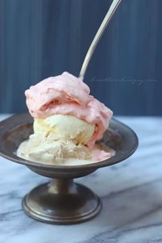 an ice cream sundae with pink icing on a black plate