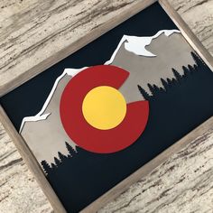 a wooden frame with the flag of colorado on it and mountains in the background at night