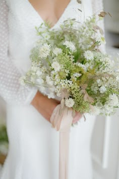 a bride holding a bouquet of white flowers