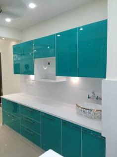 a large kitchen with green cabinets and white counter tops on the walls, along with a sink