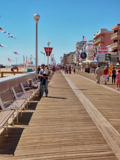 people are walking on the boardwalk near some shops