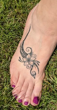 a woman's foot with a tattoo on it in the middle of some grass