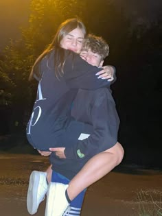 two people hugging each other outside at night