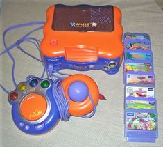 an orange and blue electronic device sitting on top of a bed next to other items