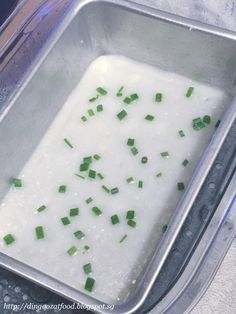 a metal pan filled with white liquid and chopped green onions