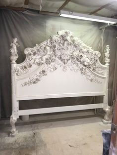 a white bed with ornate headboard and foot board in a room that is being worked on