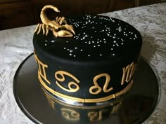 a black and gold cake with zodiac signs on it