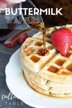 waffles with syrup being drizzled onto them and topped with strawberries