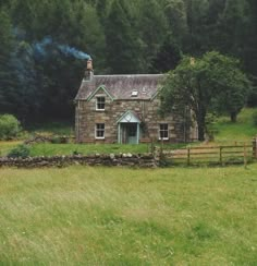 an old stone house in the middle of a field