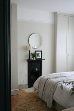 a bedroom with a bed, nightstand and mirror in it's corner next to a door