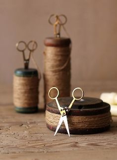 scissors and spools of thread sitting on a table next to some twine