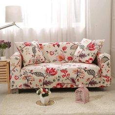 a living room filled with furniture and flowers on the floor next to a window covered in white curtains