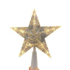 a hand holding a lighted star on top of a white pole