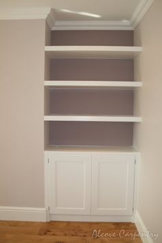 an empty white bookcase in the corner of a room