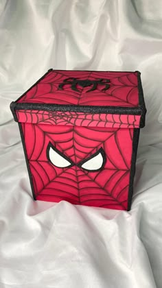 a red box with a spiderman face on it's side and eyes drawn on the front