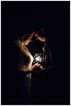 two people standing next to each other holding sparklers in their hands at night time