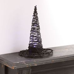 a wire christmas tree sitting on top of a black table next to a white wall