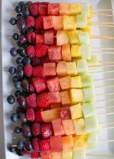 fruit skewers are arranged on a white plate