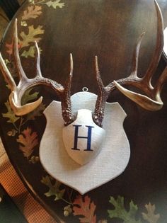 two deer antlers on top of a table with a monogrammed hat hanging from it