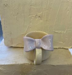 a ceramic bow tie is sitting on top of a cup in front of a wall