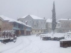 a snowy street with benches and buildings in the background