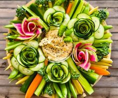 a platter filled with lots of vegetables on top of a wooden table