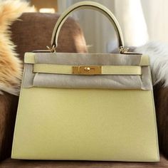 a yellow and grey purse sitting on top of a brown chair next to a furry animal