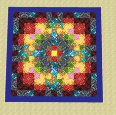 a quilted square with many different colors and designs on the front, along with a blue border