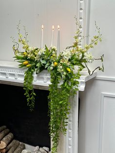 a white fireplace with candles and flowers on it