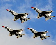 four fighter jets flying in formation against a blue sky