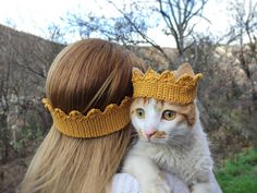 a woman holding a cat wearing a crown on her head