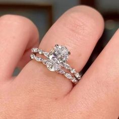 a woman's hand with a diamond ring on top of her finger and the engagement band