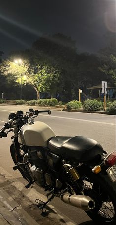 a motorcycle is parked on the side of the road at night with street lights in the background