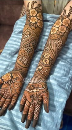 two hands with henna tattoos on them, one is showing the intricate design and the other has flowers