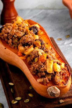 a wooden platter filled with food on top of a table next to pumpkins