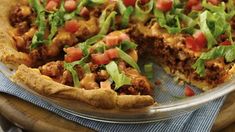 a pizza with meat, lettuce and tomato on top is shown in a pie pan