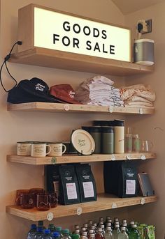 shelves with goods for sale on them and coffee cups in the bottom one, below which is a sign that reads goods for sale