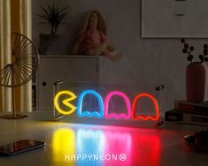 a neon sign sitting on top of a table in front of a phone and other items