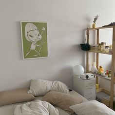 an unmade bed in a small room with a shelf on the wall behind it