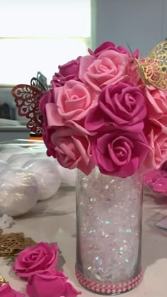 a vase filled with pink roses on top of a table next to other flowers and decorations