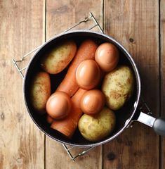 a pot filled with eggs and potatoes on top of a wooden table