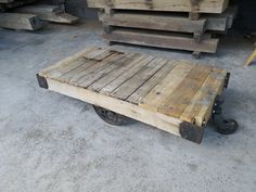 an old wooden pallet with wheels on the floor next to other wood pallets