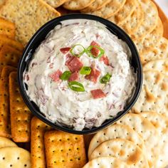 a bowl of dip surrounded by crackers on a plate